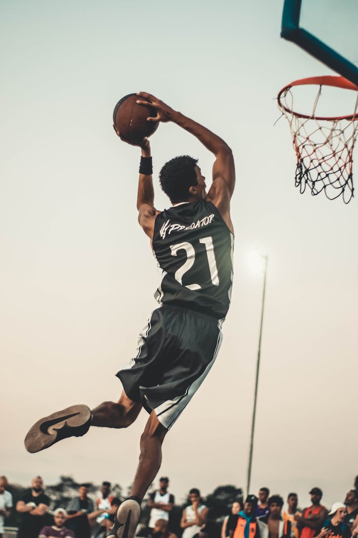 Home A dynamic basketball player executing a slam dunk during a vibrant outdoor game.